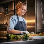 European beautiful female chef in a dark restaurant kitchen